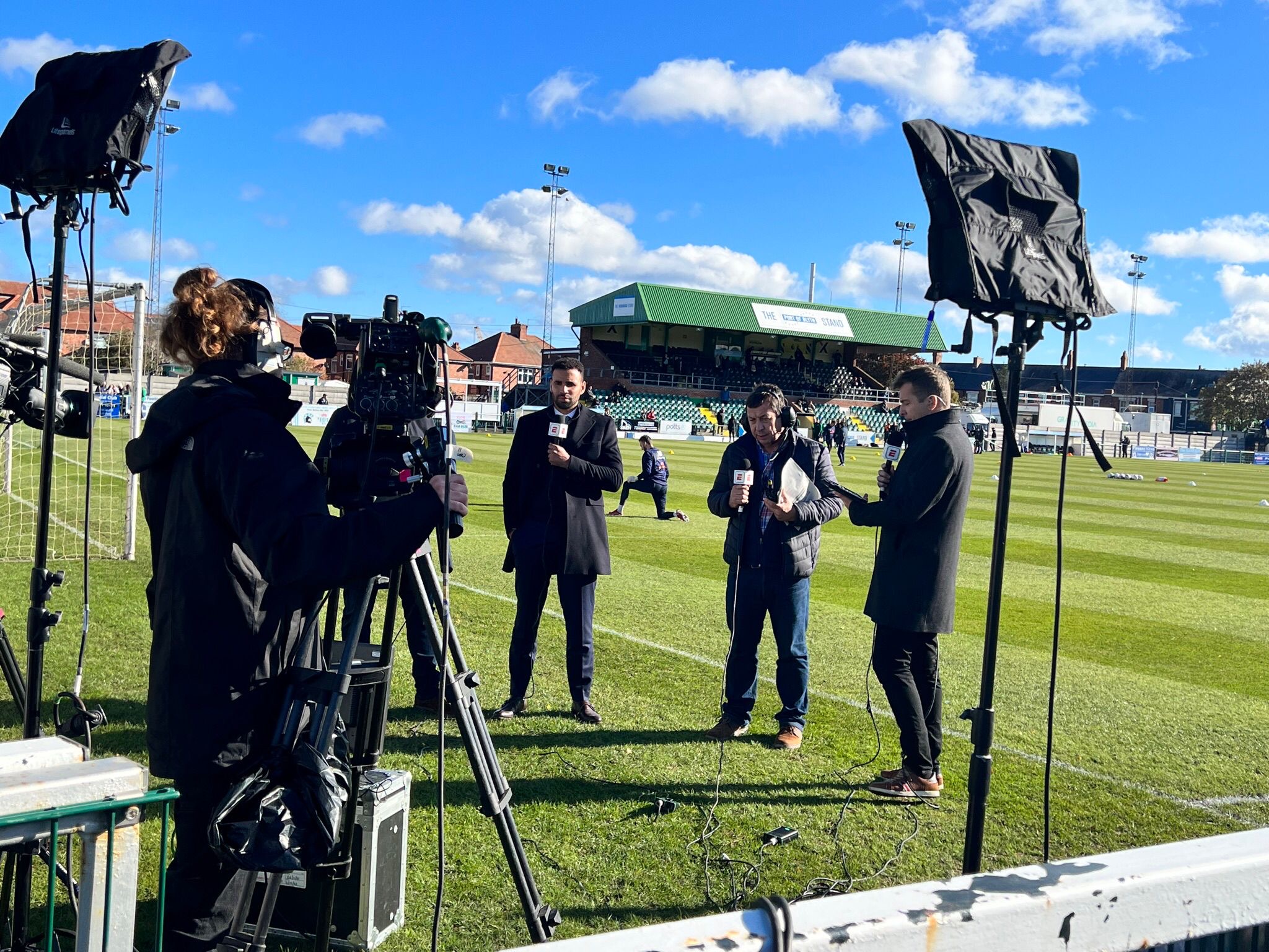 Journalist being film on football pitch.