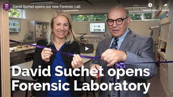 David Suchet cutting a purple ribbon in the forensics lab