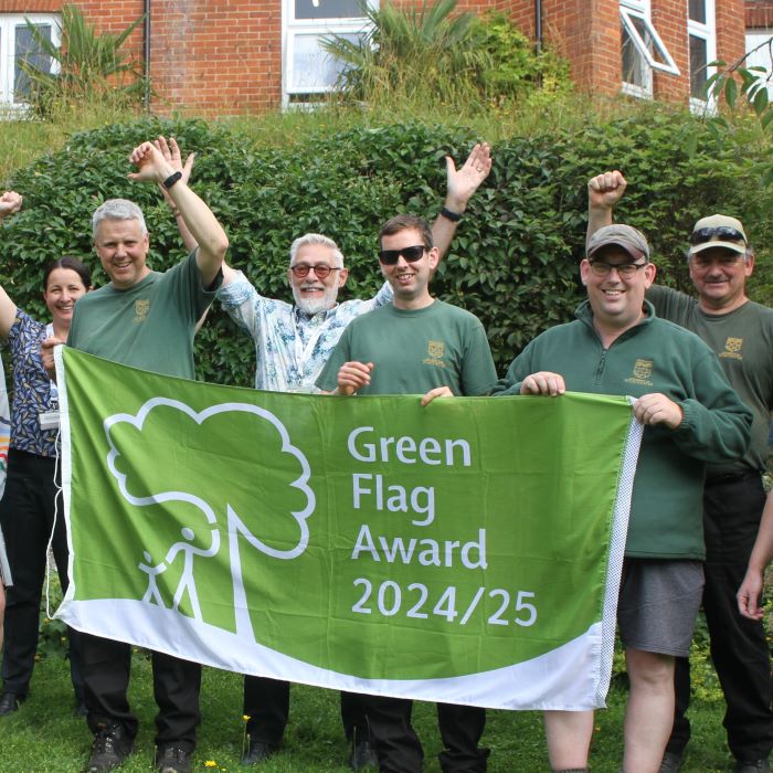 Group holding green banner emblazoned with wording Green Flag Award