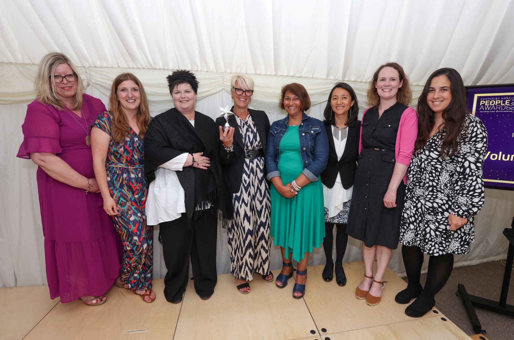 Women in marquee with a  trophy shaped like a star